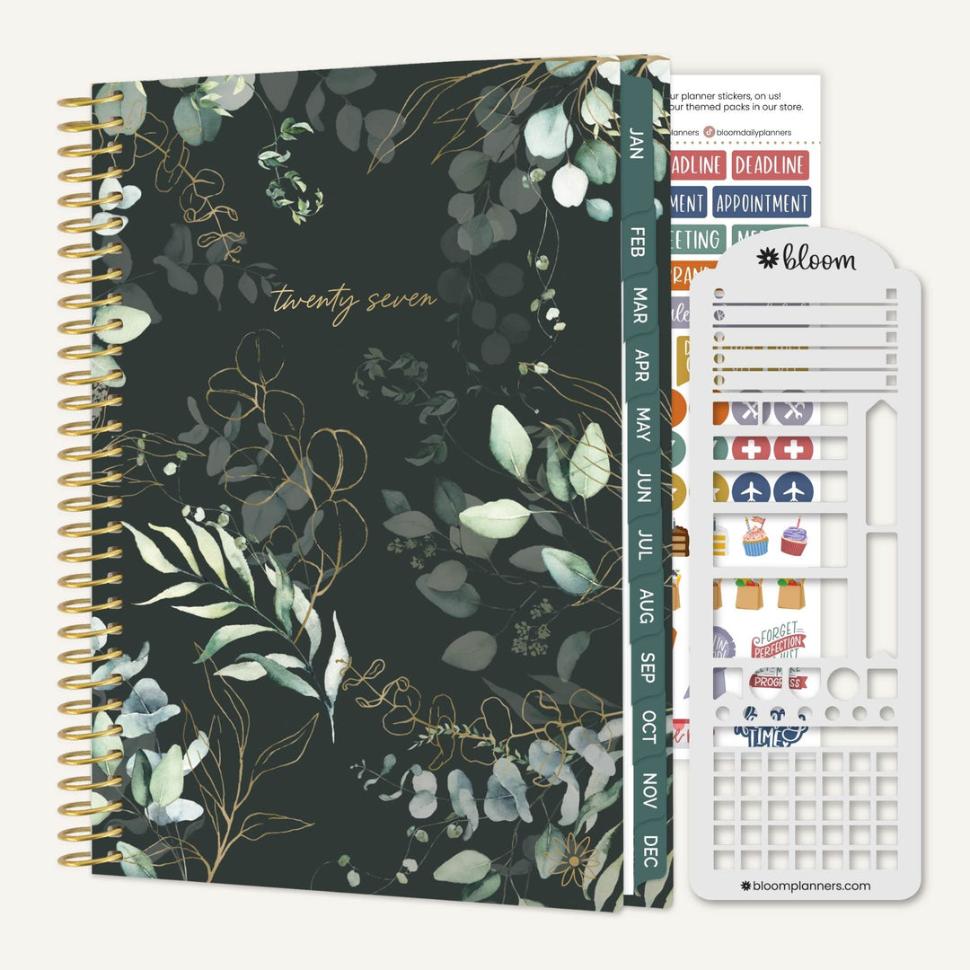 A spiral-bound planner shown with its sticker sheet and divider pages. The planner cover has a dark green background with a botanical pattern of eucalyptus leaves and gold wireframe details, with the number 'twenty seven' printed in gold near the top.