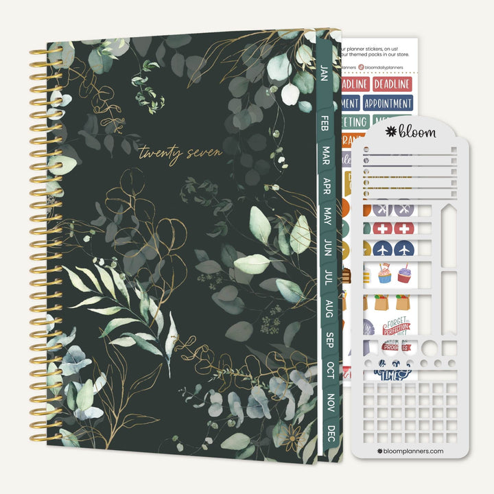 A spiral-bound planner shown with its sticker sheet and divider pages. The planner cover has a dark green background with a botanical pattern of eucalyptus leaves and gold wireframe details, with the number 'twenty seven' printed in gold near the top.