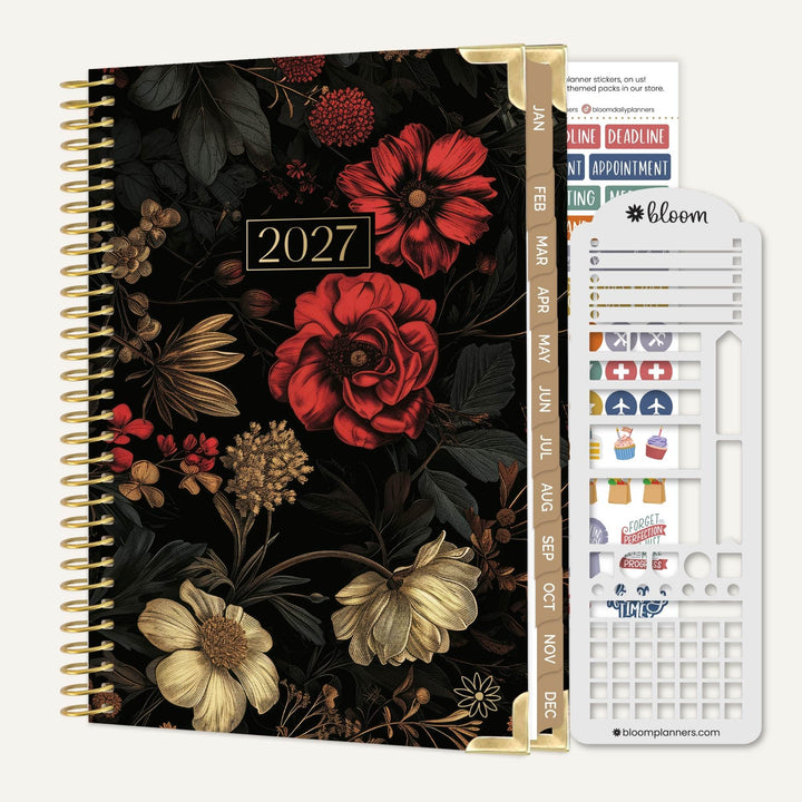 A 2027 spiral-bound planner with a dark floral cover, shown next to a white sticker sheet labeled bloom planner stickers. The cover features large red and cream flowers on a black background with gold-toned spiral binding and gold divider pages.
