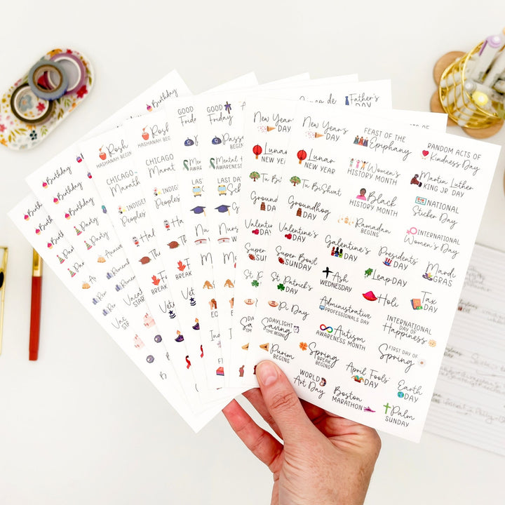 Clear-backed celebration sticker sheets, hand holding multiple sheets with colorful icons.