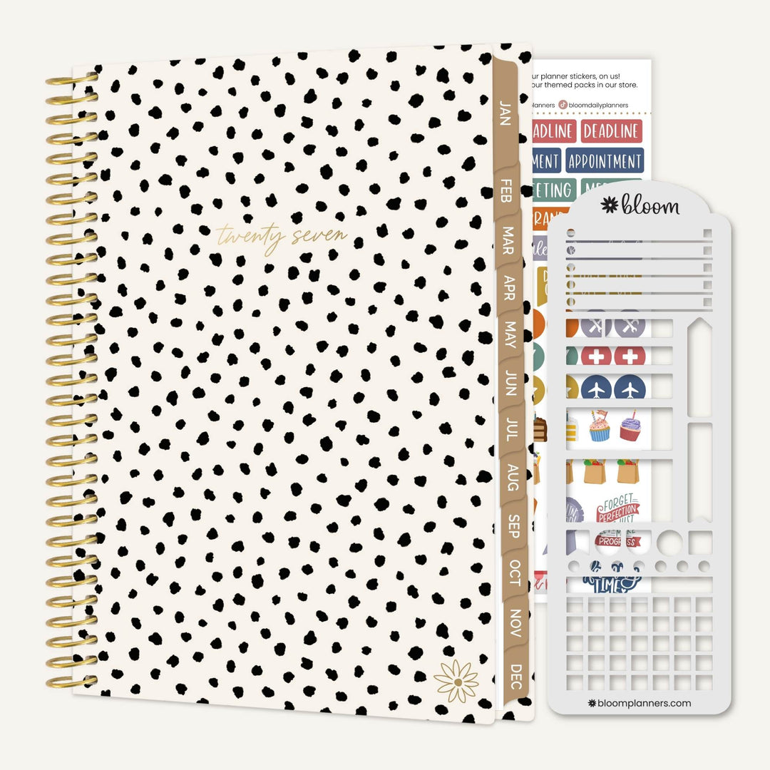 A white 12-month planner with black polka dots and gold spiral binding, shown with a white sticker sheet and planner inserts on a light gray background. The planner cover has gold foil text reading 'twenty two'.