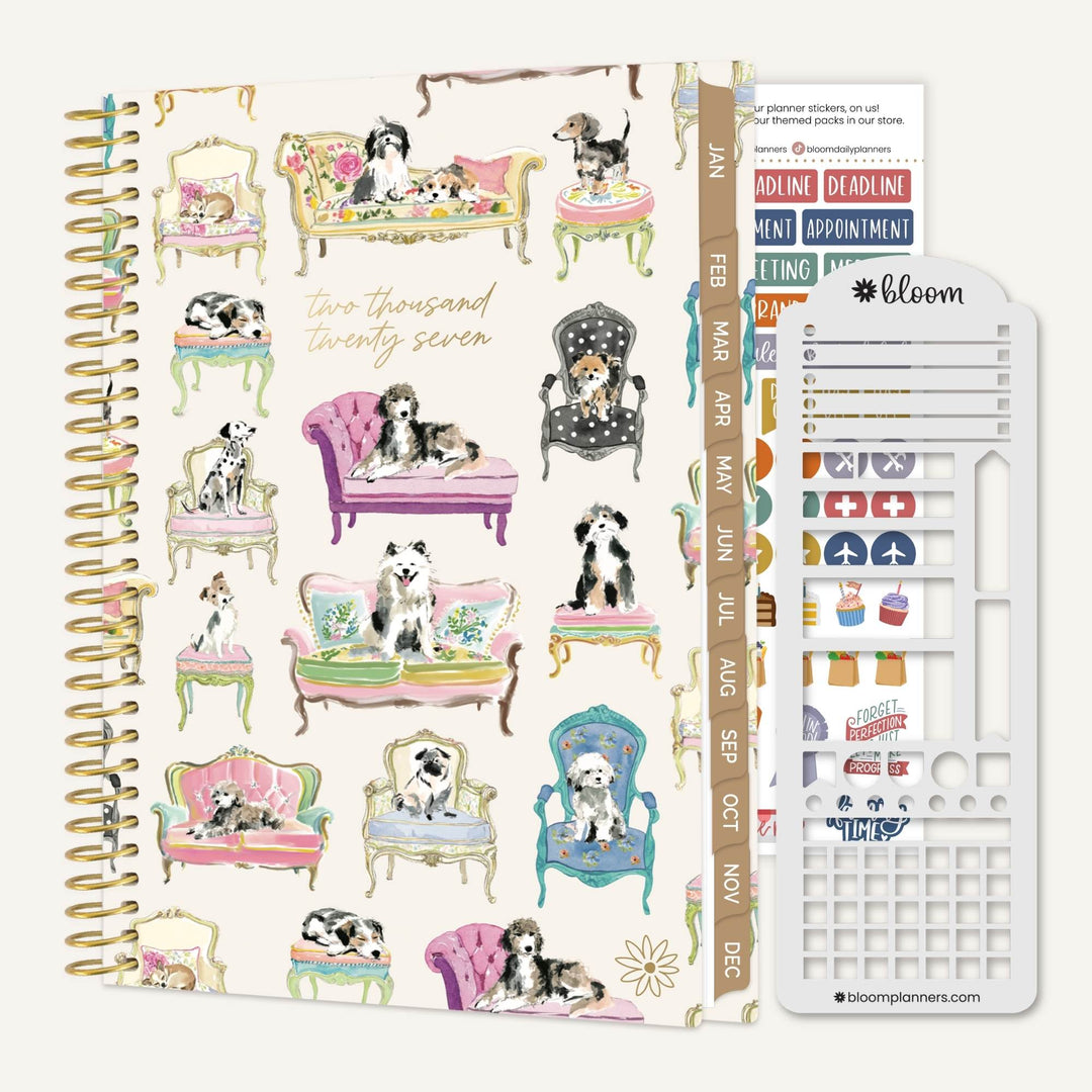 A spiral-bound planner with a cream cover decorated with vintage-style illustrations of dogs sitting in colorful chairs, shown alongside sticker sheets and a white planner insert tool. The cover includes the text 'Two thousand twenty seven' and a vertical date strip labeled JAN through DEC.