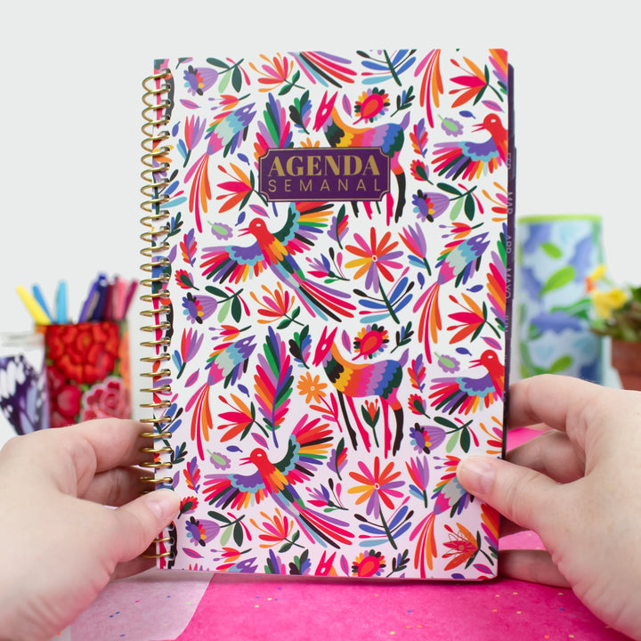 Colorful agenda with floral and animal pattern held by hands against a blurred background