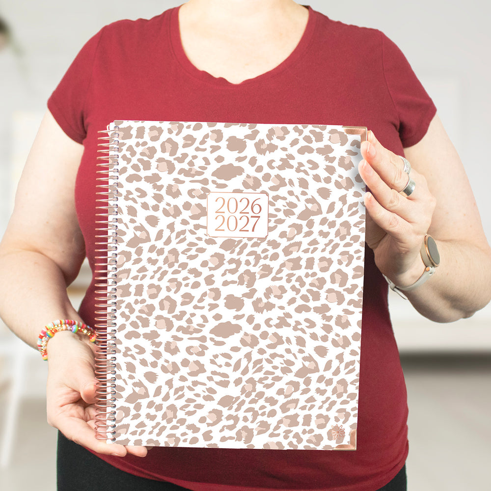 Person holding a 2026-2027 planner with a leopard print cover