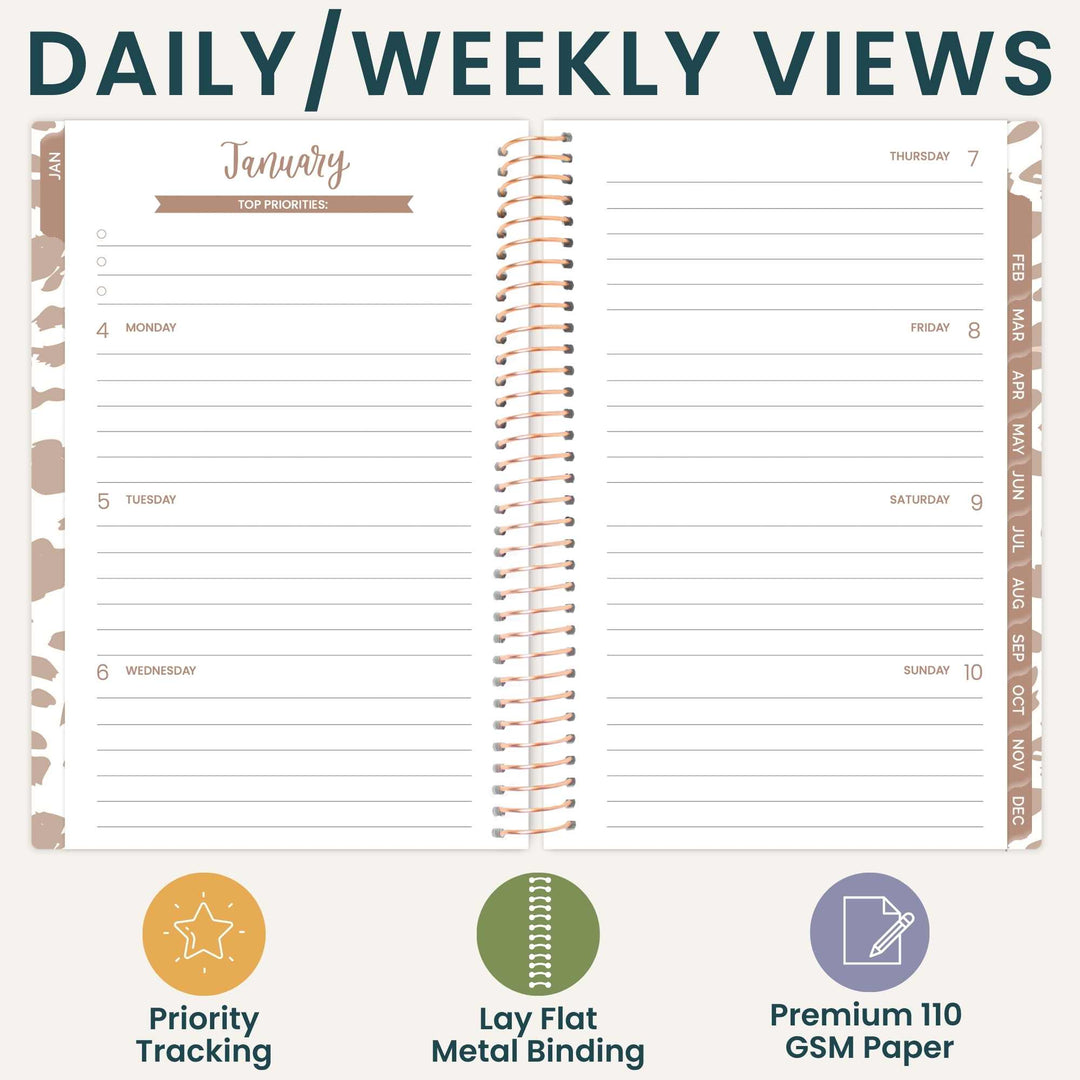 An open spiral-bound planner shown on a light beige background with the headline 'DAILY/WEEKLY VIEWS' at the top and three feature icons below: priority tracking, lay flat metal binding, and premium 110 GSM paper.