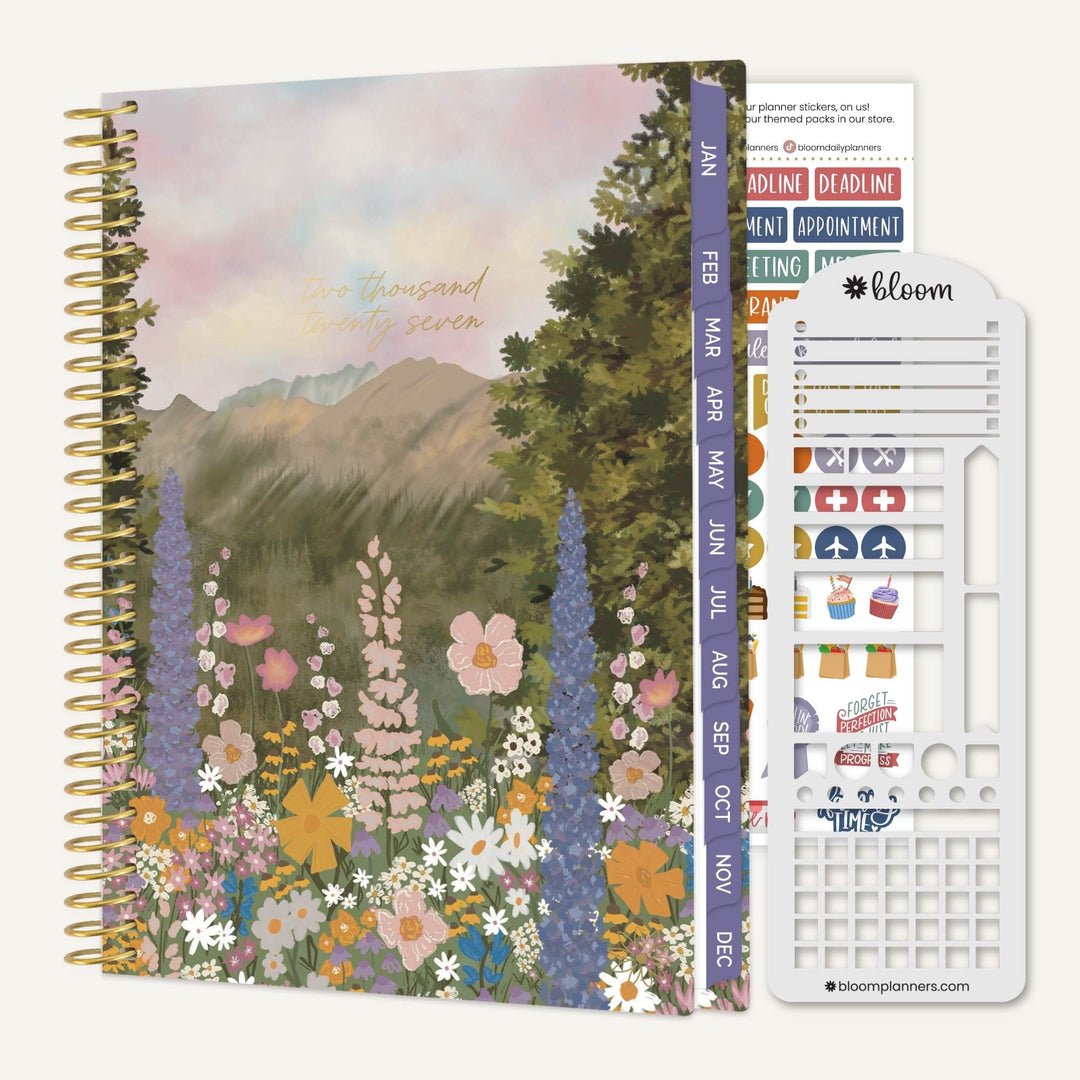A spiral-bound planner or journal with a floral mountain landscape cover, shown next to a white sticker sheet and a vertical planner tab strip. The cover features pastel flowers, trees, and mountains with the text 'thousand and seven hundred and seventy seven'.