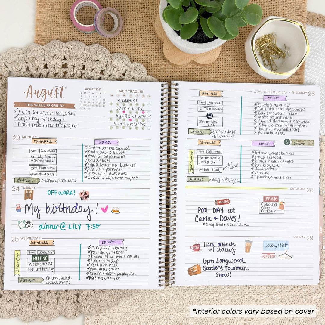 An open spiral-bound planner shown from above on a beige textured surface with a crocheted lace cloth underneath. The planner pages are filled with handwritten notes, weekly layouts, and colorful decorative accents.
