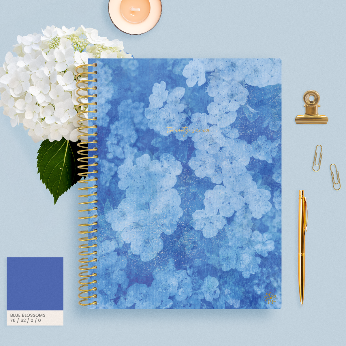 bloom 2027 planner with a Blue Hydrangea cover design on a desk with flowers. 