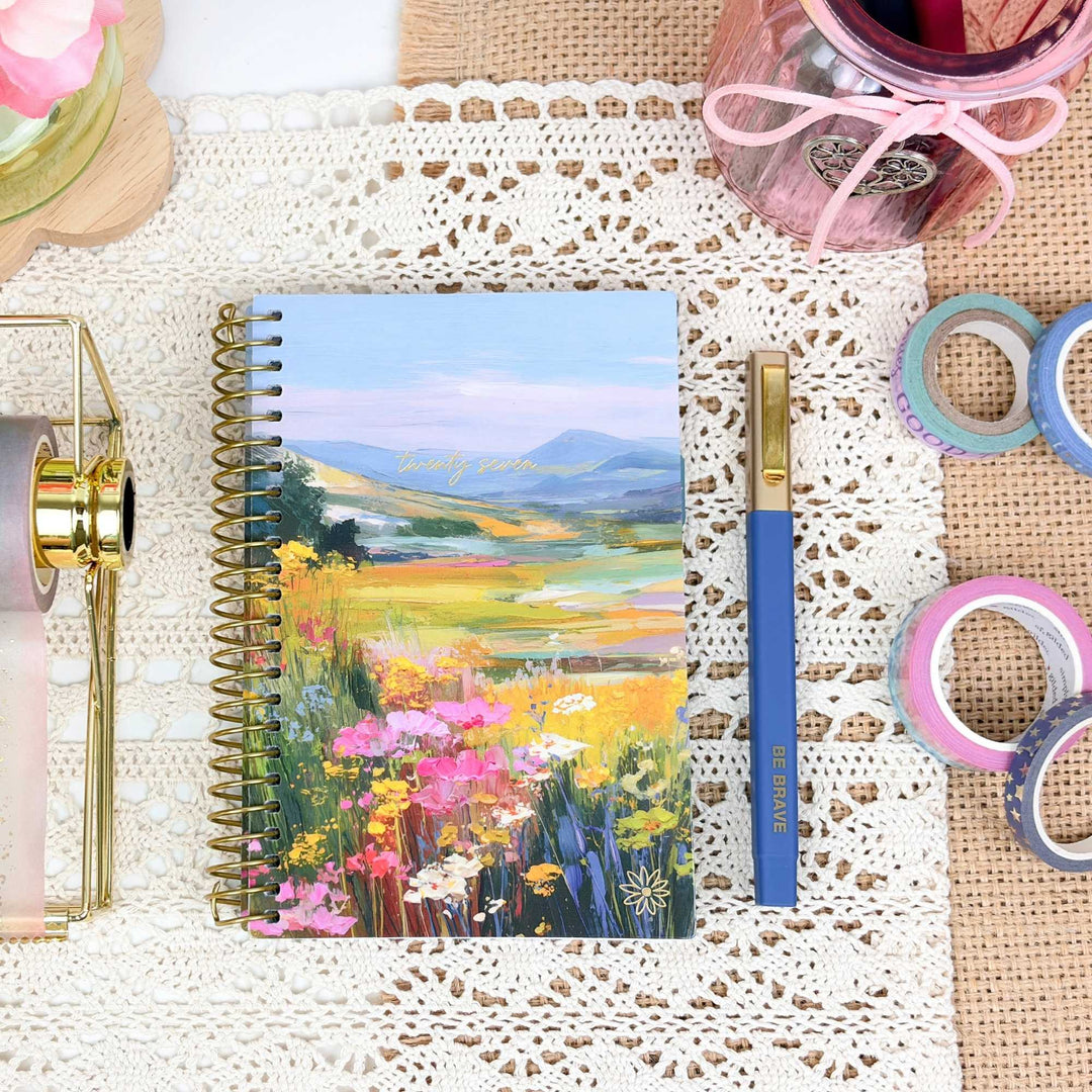 Notebook with floral cover on a textured surface with stationery items