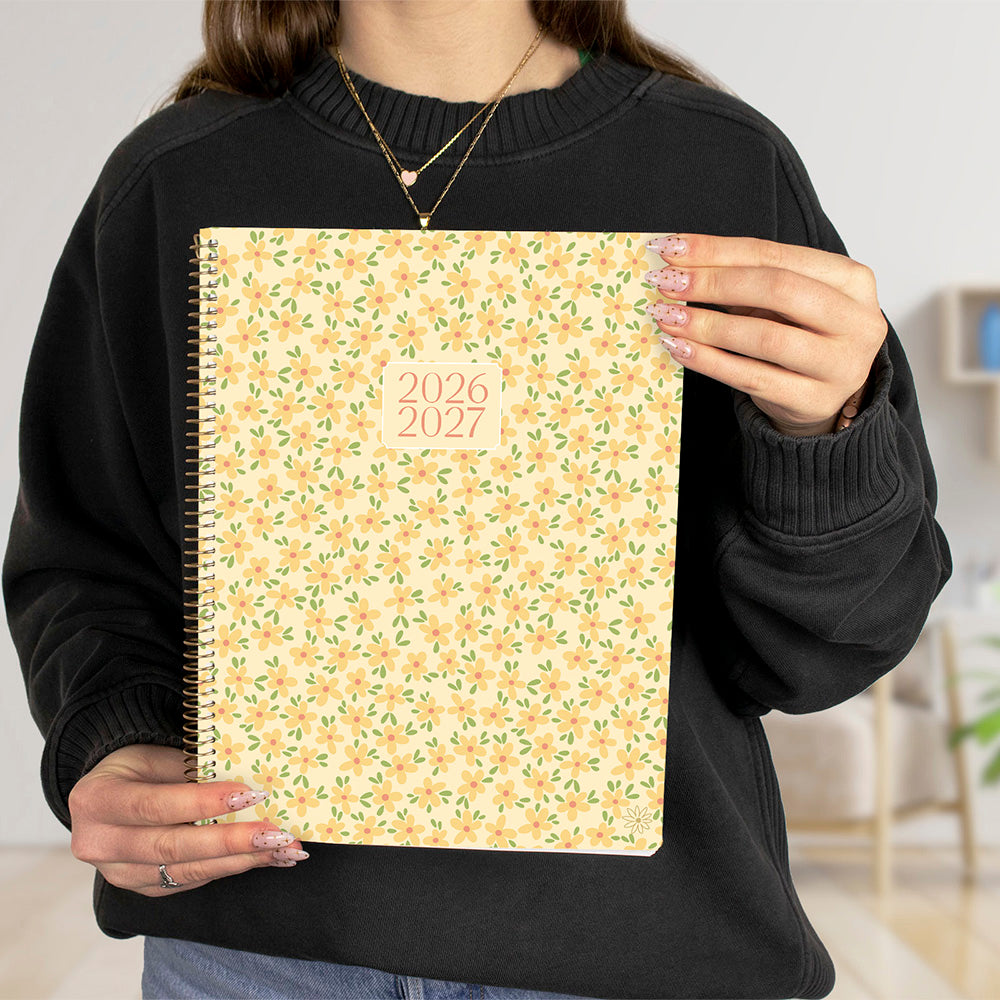 Person holding a 2026-2027 floral-patterned planner