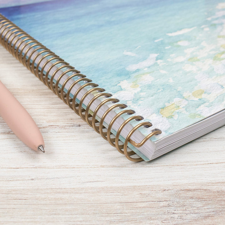 Spiral-bound planner with a pen on a wooden surface