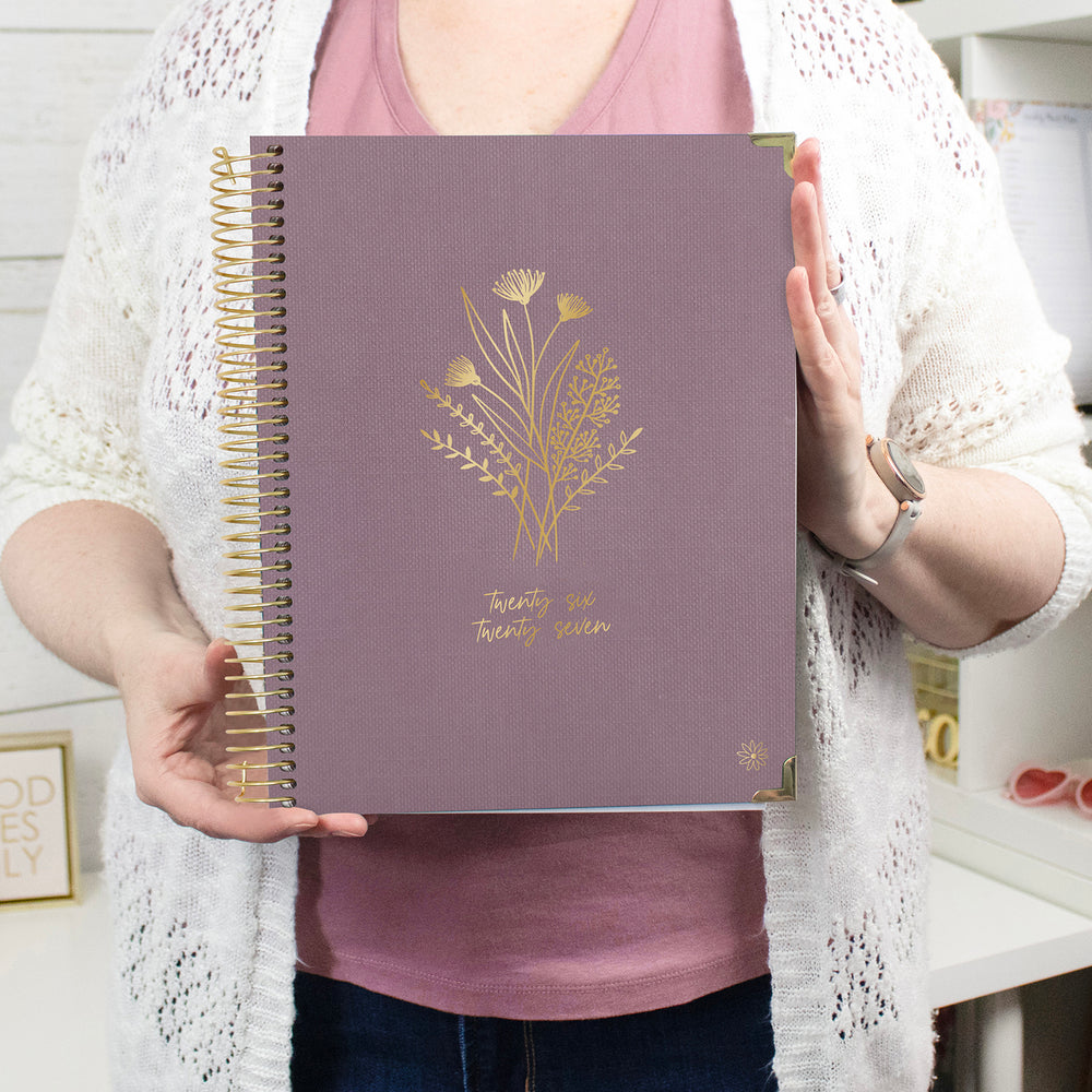 Person holding a purple planner with gold floral design