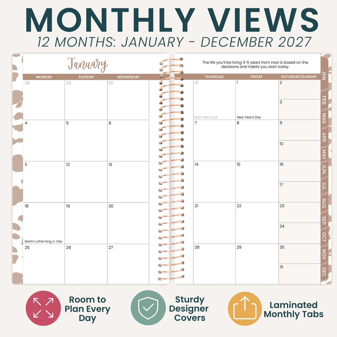 A 12-month monthly planner spread showing January through December 2027, with a spiral binding design and decorative beige and brown patterned borders. The top text reads 'MONTHLY VIEWS 12 MONTHS: JANUARY - DECEMBER 2027,' and the bottom has three feature icons with text: 'Room to Plan Every Day,' 'Sturdy Designer Covers,' and 'Laminated Monthly Tabs.