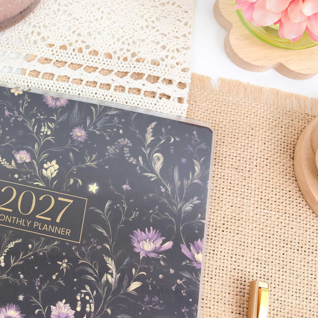 Floral 2027 planner on a textured surface with a pen