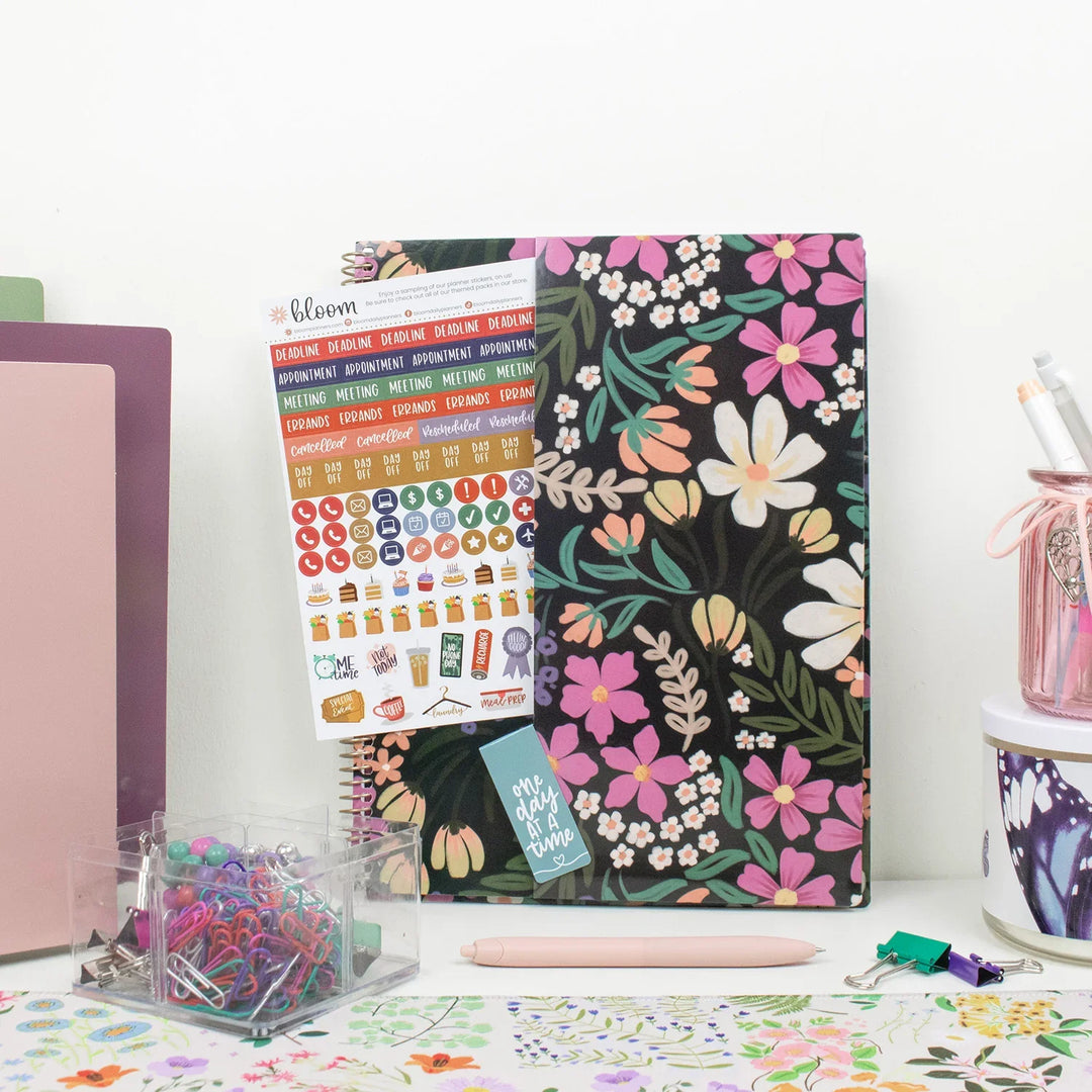 Floral planner with planner stickers and stationery items on a desk