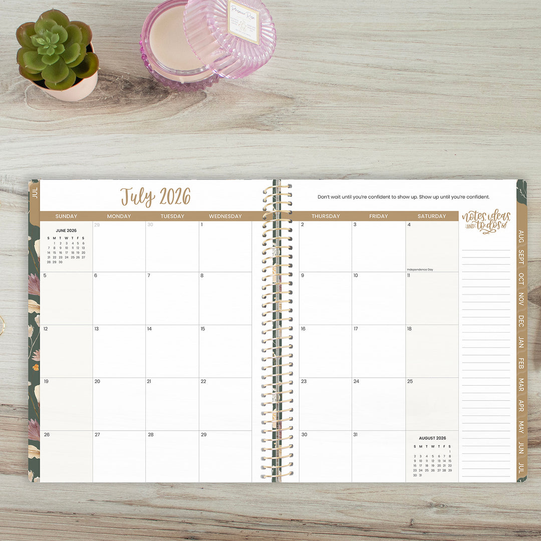 Open planner showing July 2026 on a wooden surface with a plant and candle.