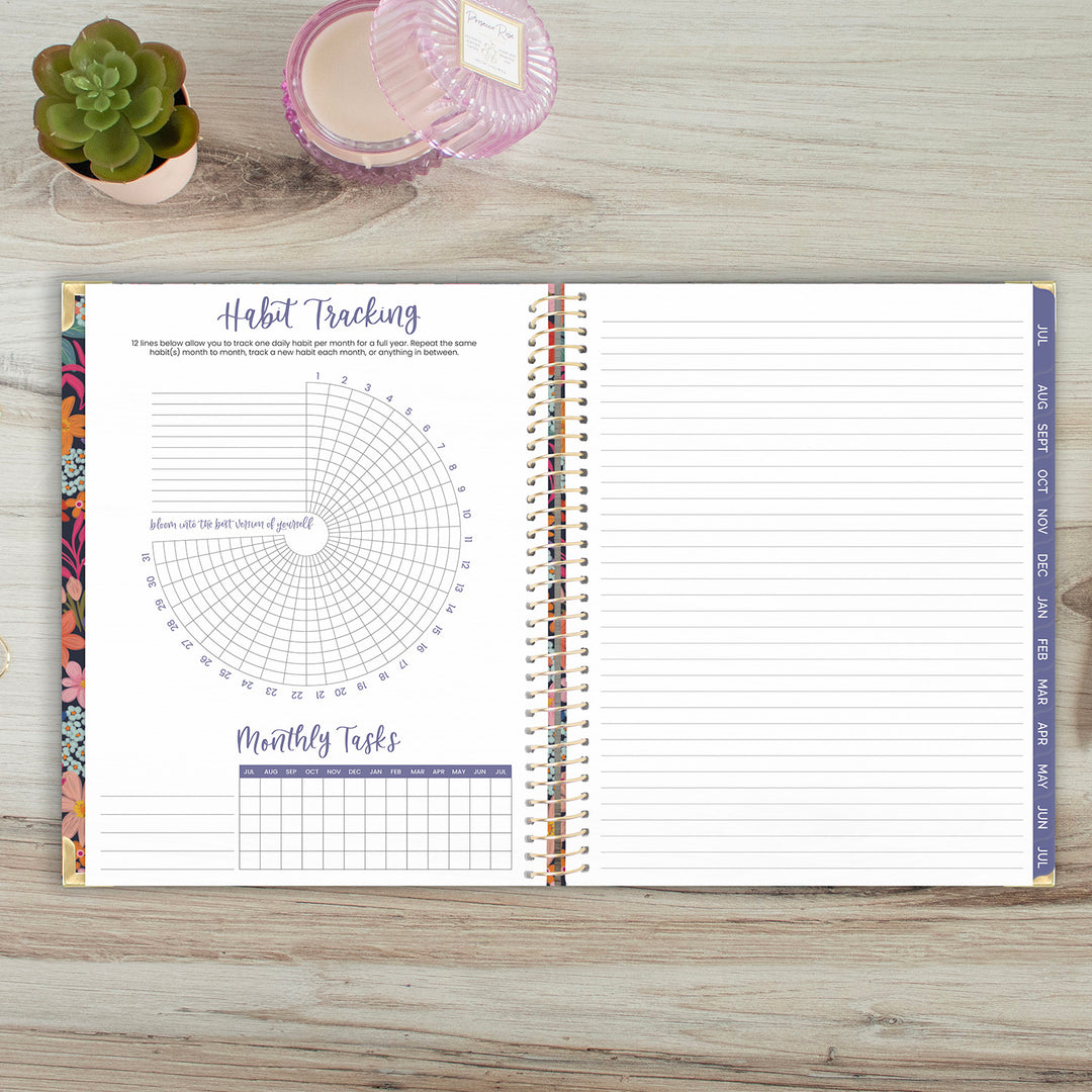 Open planner with habit tracking and monthly tasks on a wooden surface with a plant and candle.