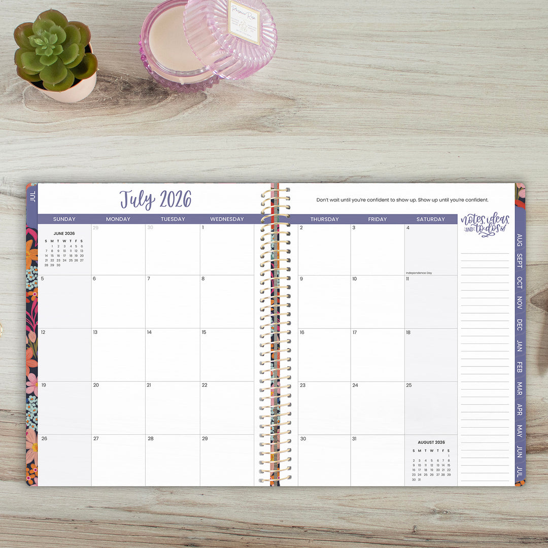Calendar planner for July 2026 on a wooden surface with decorative items.