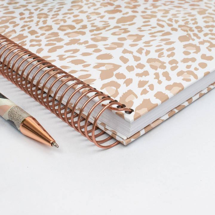 Planner with leopard print cover and copper spiral binding on a white background