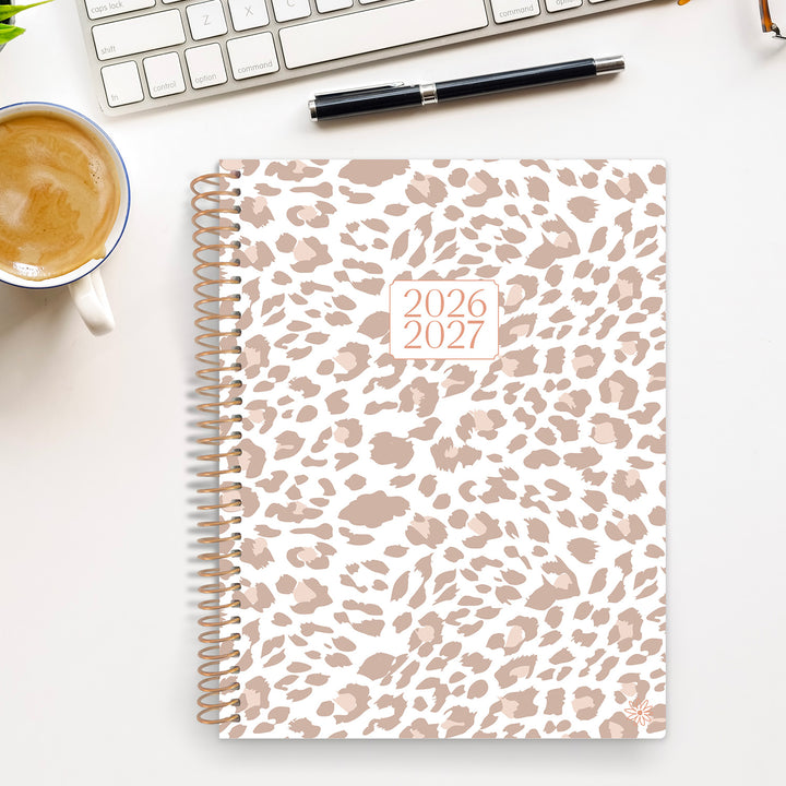 Leopard print planner for 2026-2027 on a desk with a cup of coffee and pen.