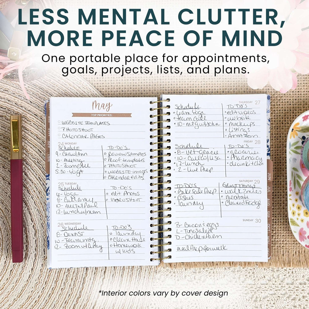 An open spiral-bound planner shown on a burlap-style background with decorative floral and ribbon props. The planner pages are white with handwritten notes and a gold-toned header, and large marketing text at the top reads, 'LESS MENTAL CLUTTER, MORE PEACE OF MIND.