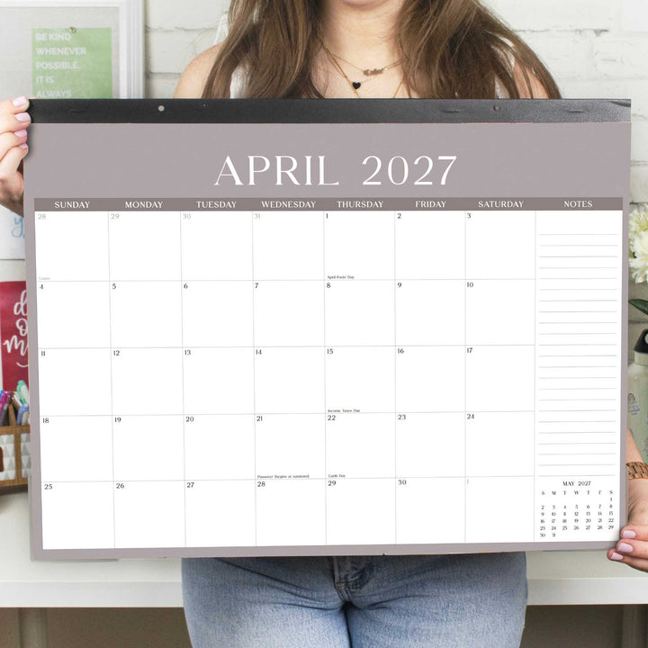Person holding a large calendar displaying April 2027.