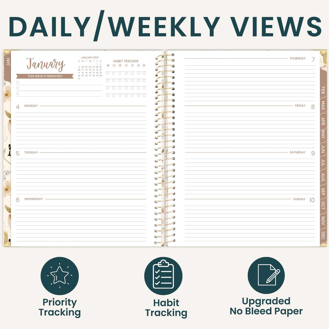 An open spiral-bound planner shown on a light beige background with the heading 'DAILY/WEEKLY VIEWS' at the top. The planner pages are white with dark teal lines and text, gold ring binding, and tan/beige accent bands.