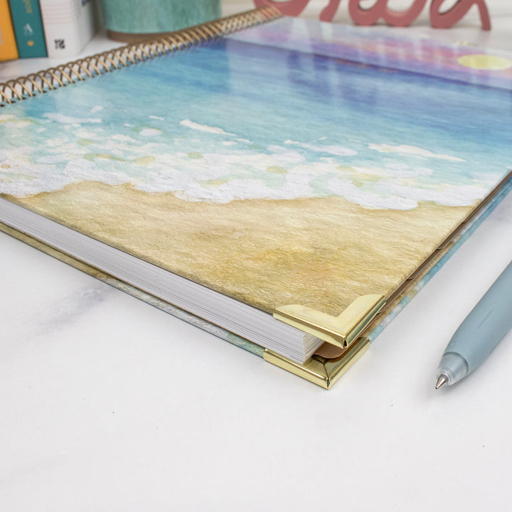 Planner with beach design cover on a white surface