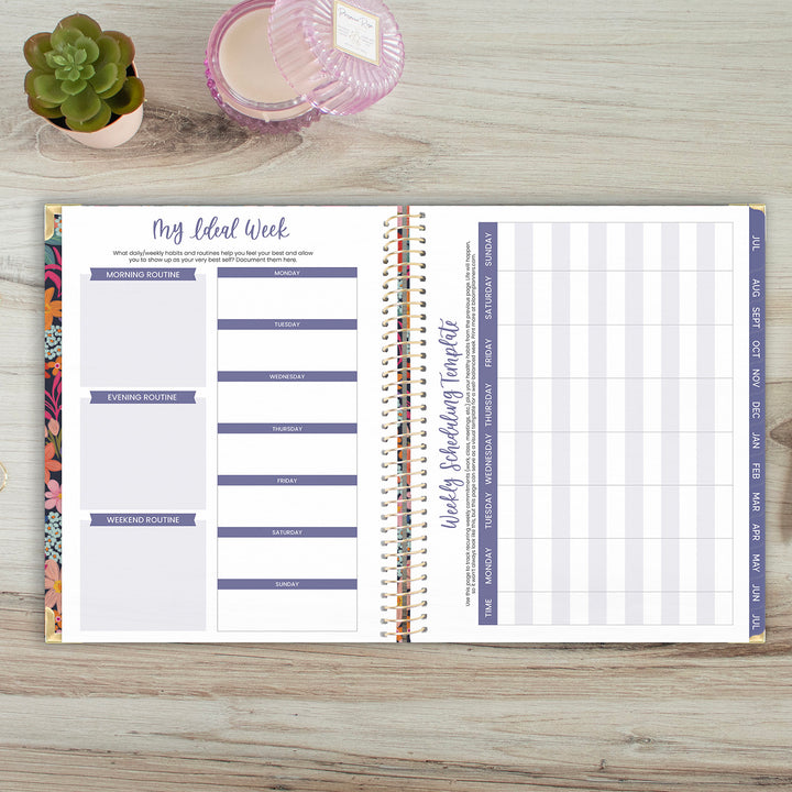 Open planner on a wooden surface with a small plant and pink container in the background