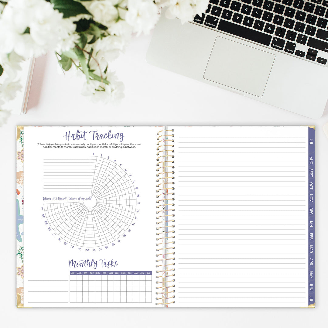 Open spiral-bound planner with habit tracking and monthly tasks on a desk with laptop and flowers.
