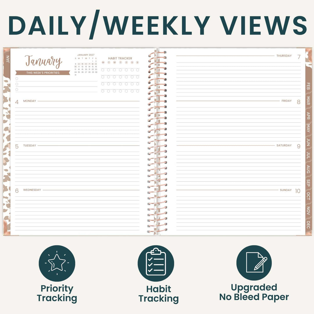 An open spiral-bound planner shown from the front with a daily and weekly view layout, titled 'DAILY/WEEKLY VIEWS.' The planner has lined pages, date columns, weekday sections, and tracking areas for priorities and habits.
