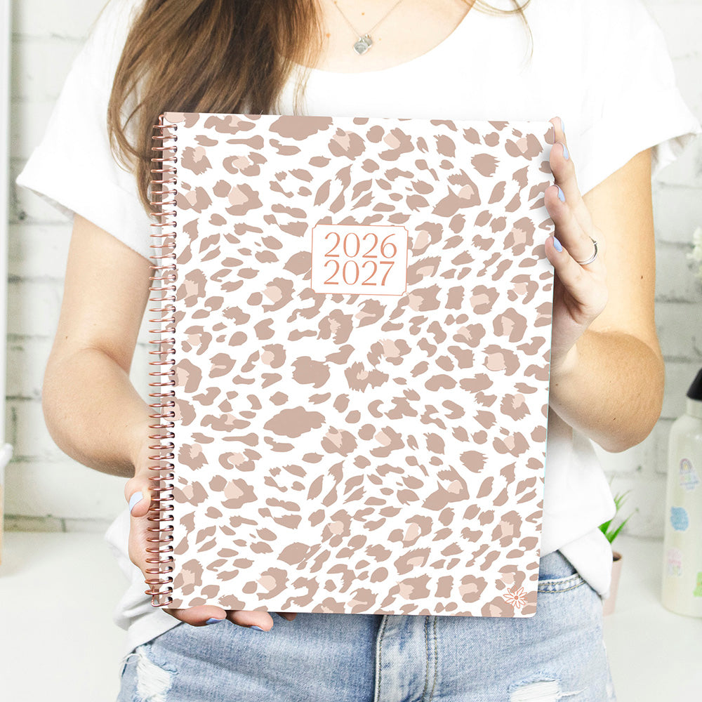 Person holding a 2026-2027 planner with a leopard print cover