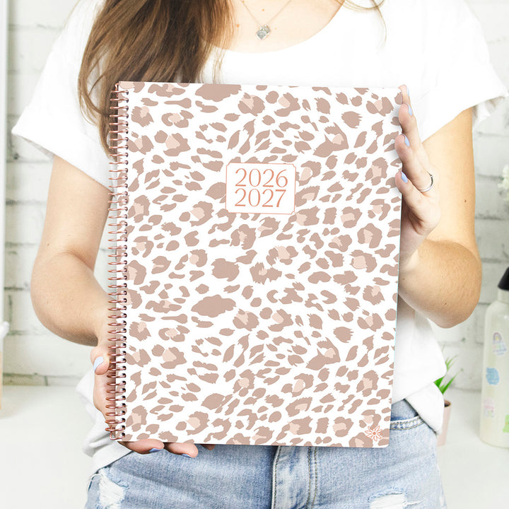 Person holding a 2026-2027 planner with a leopard print cover