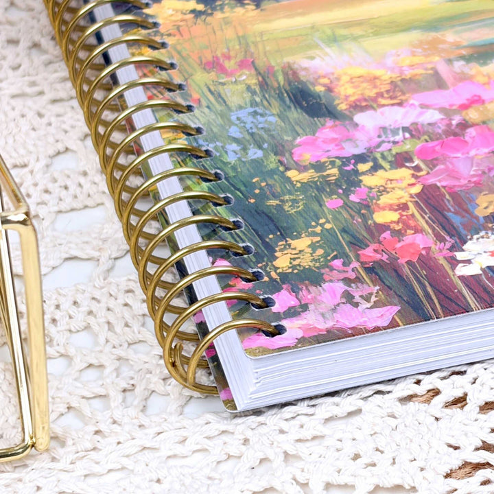 planner with floral design on cover and gold spiral binding on textured surface