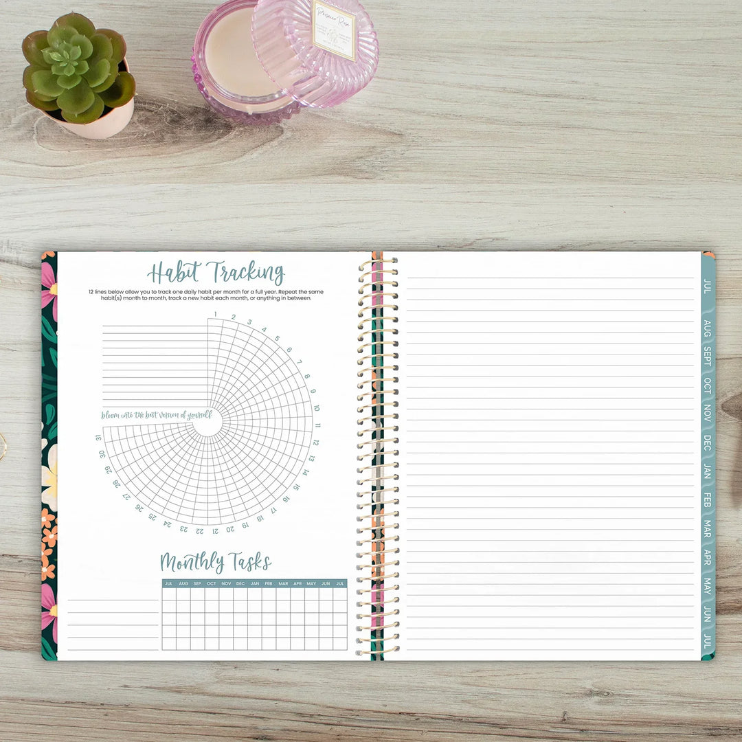 Open planner with habit tracking page on a wooden surface with a plant and candle.