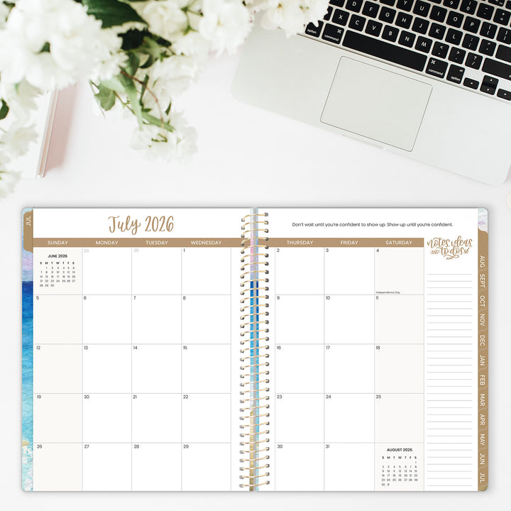 Open planner showing July 2026 with a laptop and flowers in the background