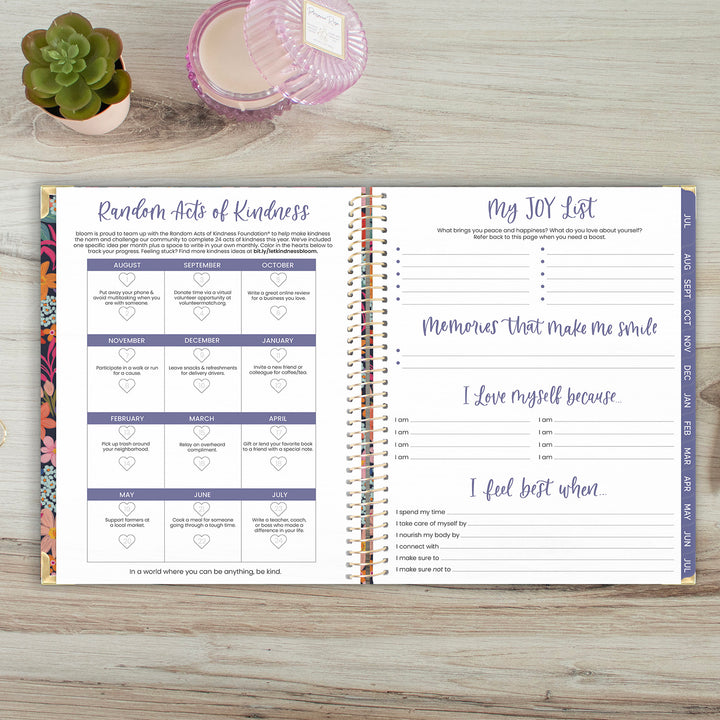 Open planner with sections for 'Random Acts of Kindness' and 'My JOY List' on a wooden surface.