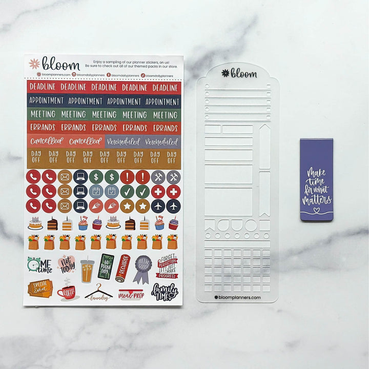 Bloom planner sticker kit and coordinating metal template set on a white marble background. The kit includes a sheet of colorful planner stickers, a white metal grid template, and a purple planner tape roll.