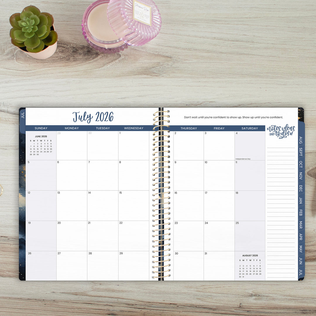 Open planner showing July 2026 on a wooden surface with a plant and candle.