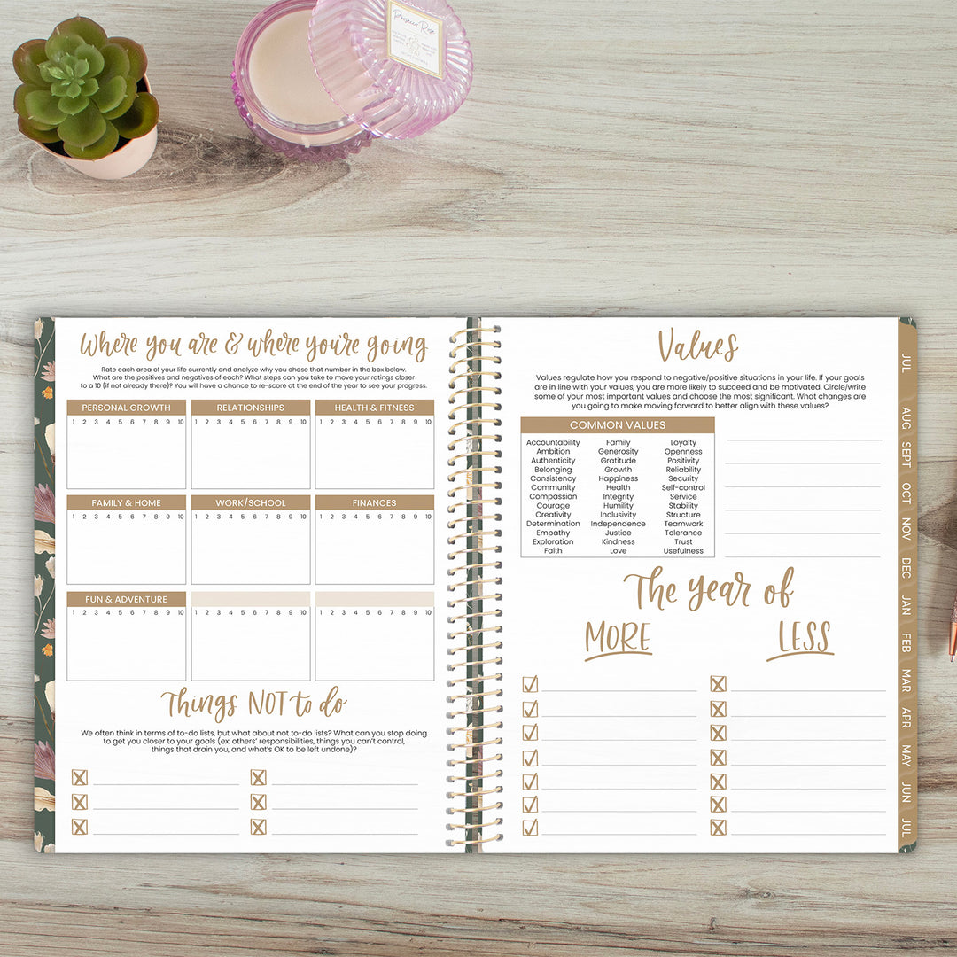 Open planner on a wooden surface with a succulent plant and glass container in the background