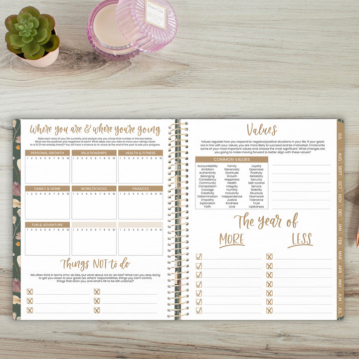 Open planner on a wooden surface with a succulent plant and glass container in the background