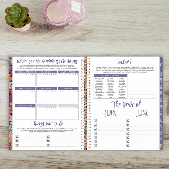 Open planner on a wooden surface with a plant and candle in the background