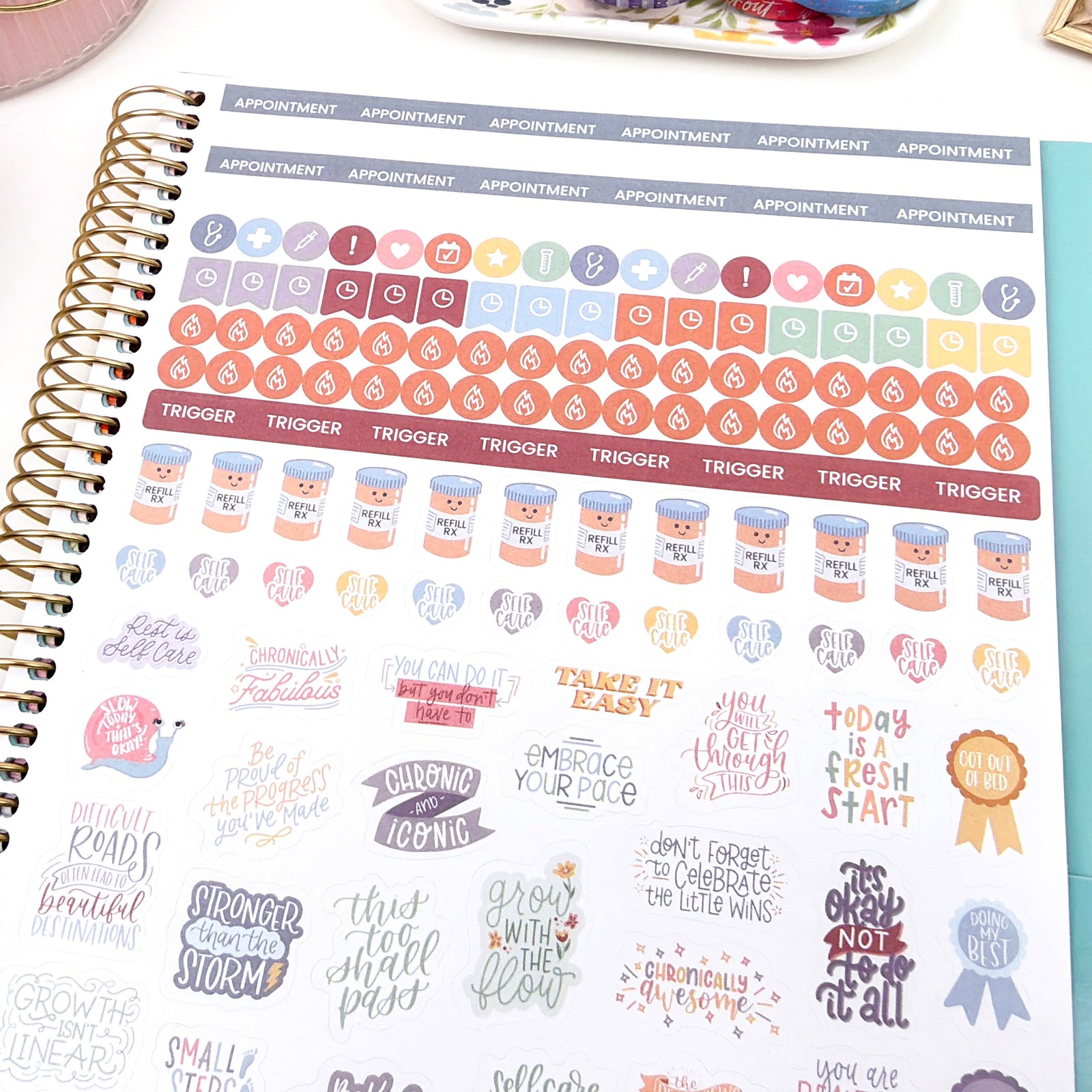 Spiral-bound chronic illness planner with decorative health and wellness medical themed stickers on a desk with stationery items.