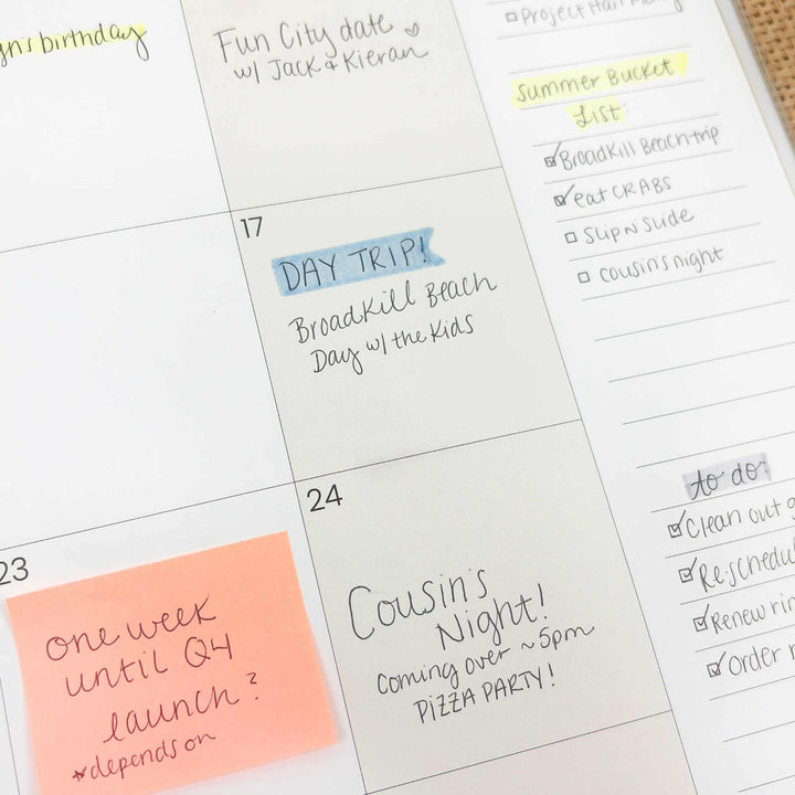 Calendar with handwritten notes and a post-it note on a white surface