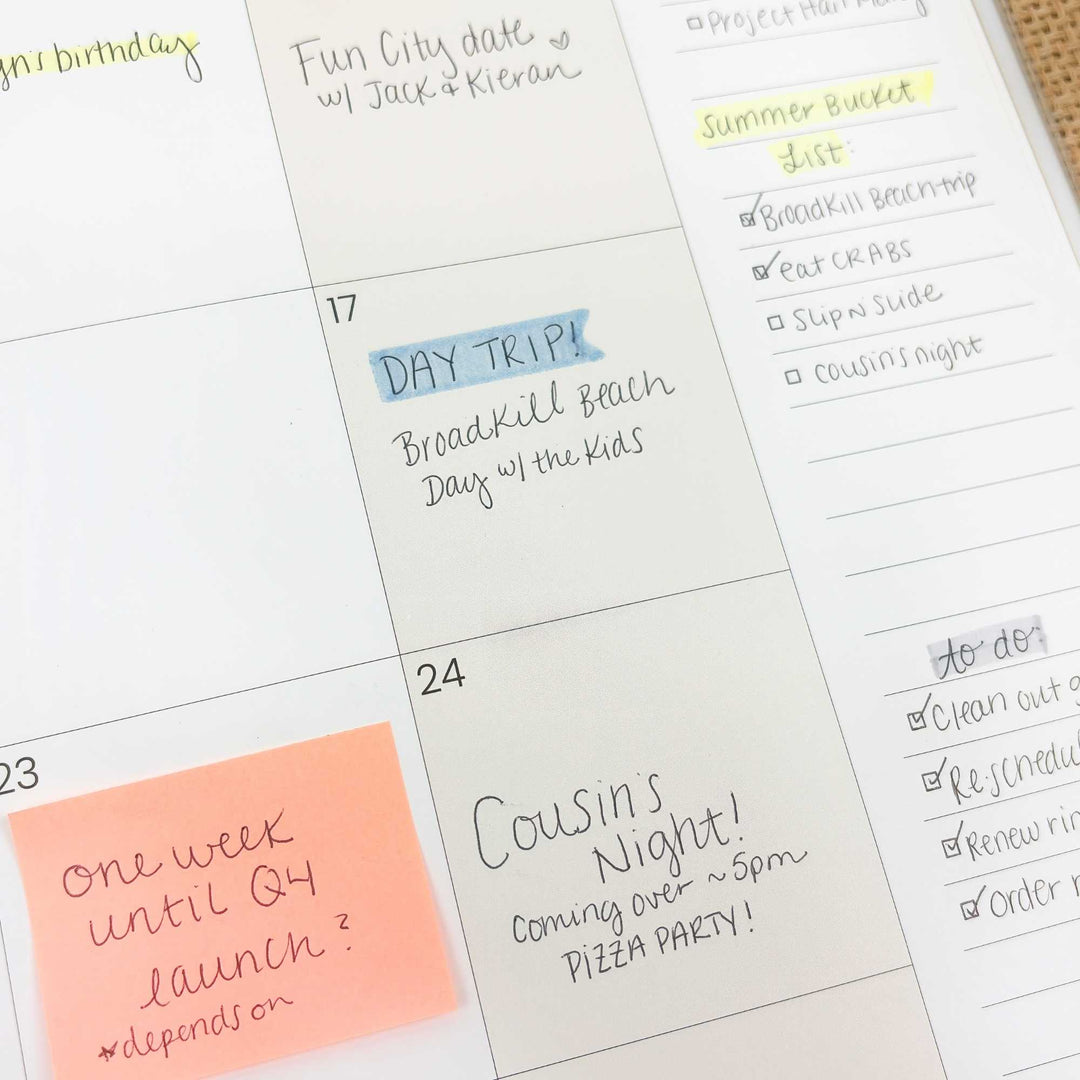 Calendar with handwritten notes and a post-it note on a white surface
