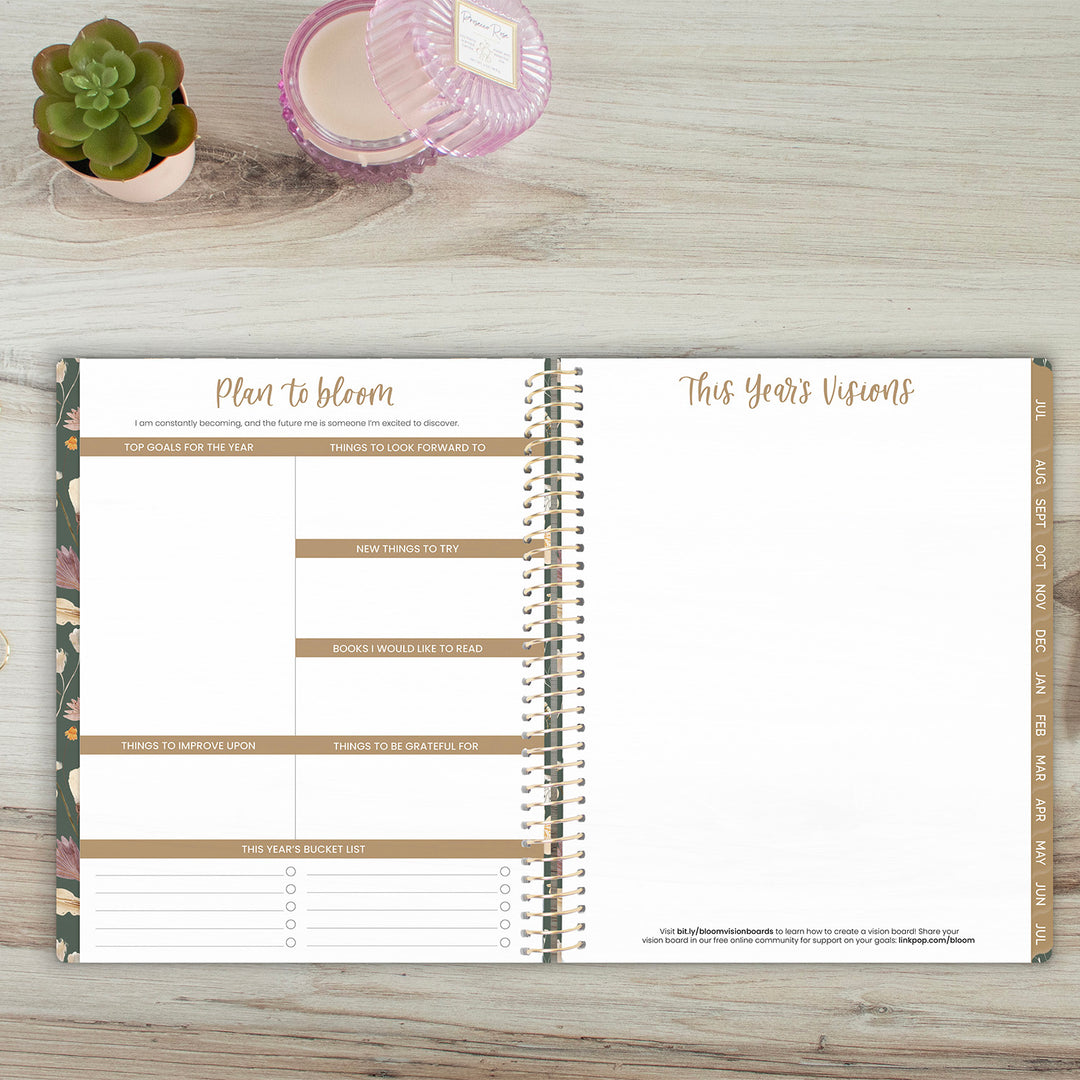 Open planner on a wooden surface with a plant and candle in the background