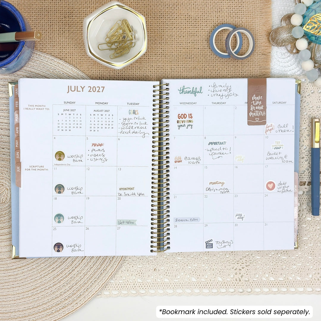 Open Christian planner with spiral binding and dated July 2027 monthly view