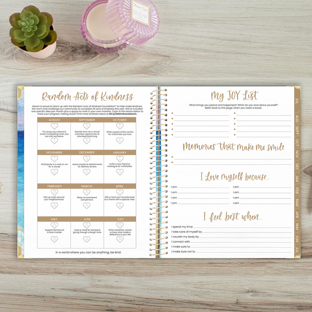 Open planner on a wooden surface with 'Random Acts of Kindness' and 'My JOY List' sections.