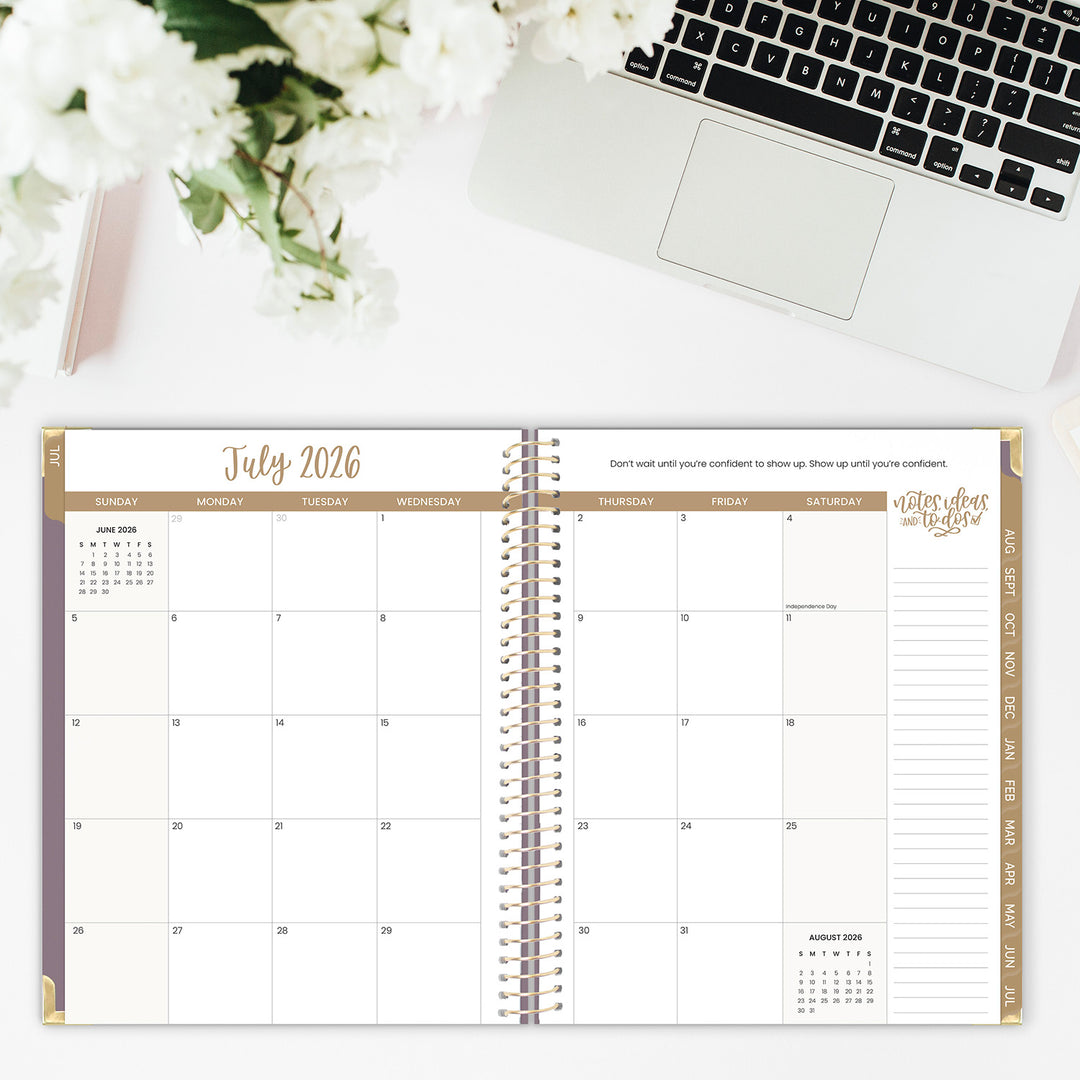 Calendar open to July 2026 with a laptop and flowers in the background