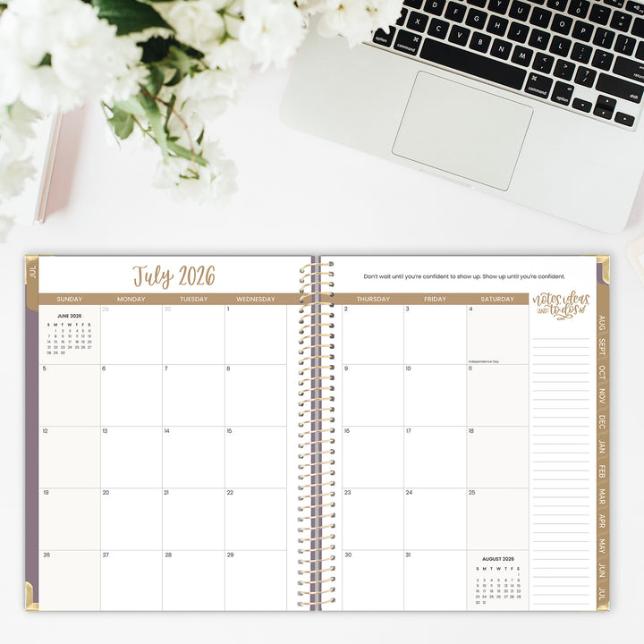 Calendar open to July 2026 with a laptop and flowers in the background